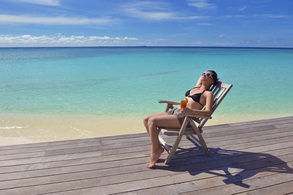 Mooie jonge vrouw met een drankje bij de zee — Stockfoto