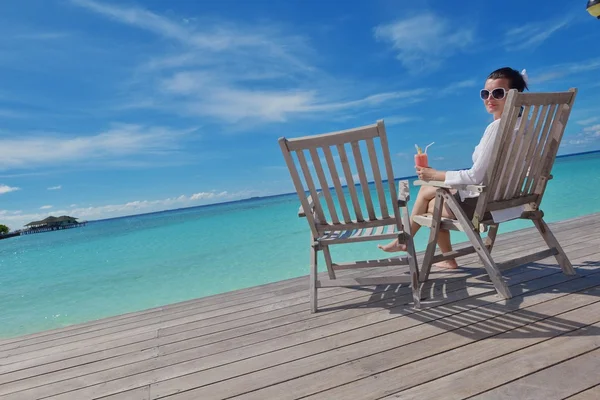 Mooie jonge vrouw met een drankje bij de zee — Stockfoto