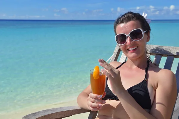 Beautiful young woman with a drink by the sea — Stock Photo, Image