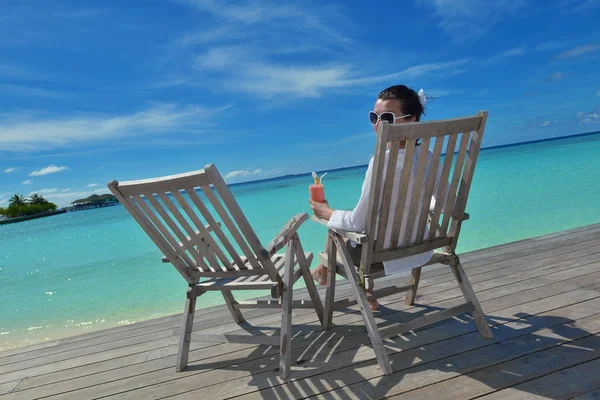 Hermosa joven con una bebida junto al mar — Foto de Stock