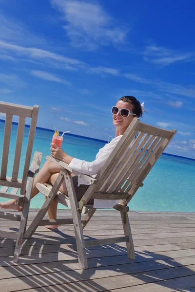 Beautiful young woman with a drink by the sea — Stock Photo, Image