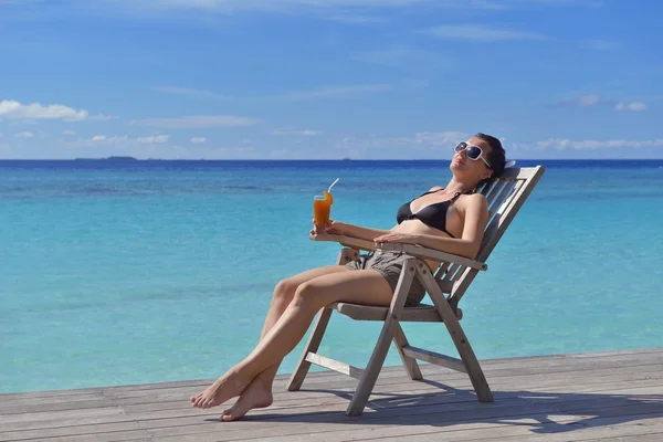 Beautiful young woman with a drink by the sea — Stock Photo, Image