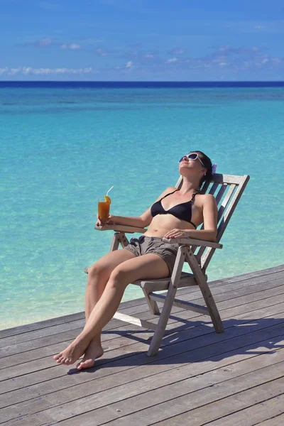 Beautiful young woman with a drink by the sea — Stock Photo, Image