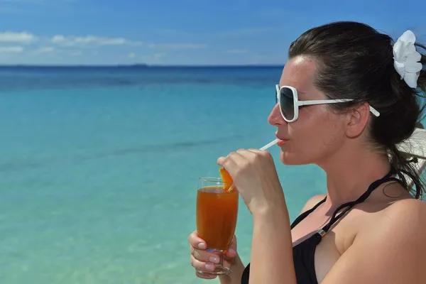 Beautiful young woman with a drink by the sea — Stock Photo, Image