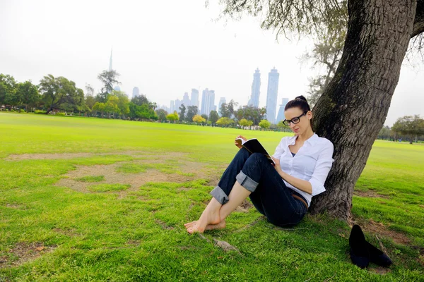 Jonge vrouw leest een boek in het park — Stockfoto