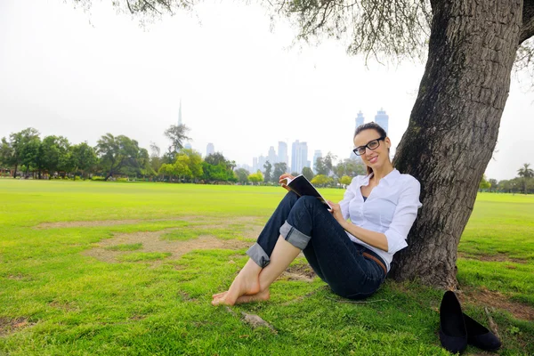 Jeune femme lisant un livre dans le parc — Photo