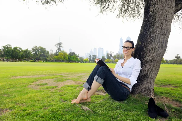 Jonge vrouw leest een boek in het park — Stockfoto