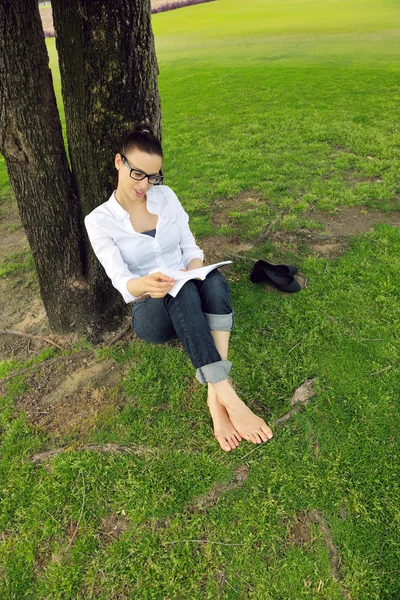 Jonge vrouw leest een boek in het park — Stockfoto