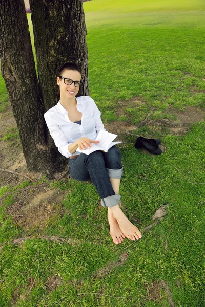 Νεαρή γυναίκα διαβάζει ένα βιβλίο στο πάρκο — Φωτογραφία Αρχείου