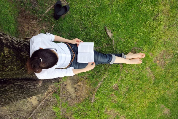 Jonge vrouw leest een boek in het park — Stockfoto