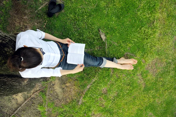 Jonge vrouw leest een boek in het park — Stockfoto