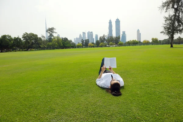 公園で本を読んでいる若い女性が — ストック写真