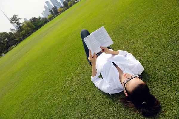 Jonge vrouw leest een boek in het park — Stockfoto