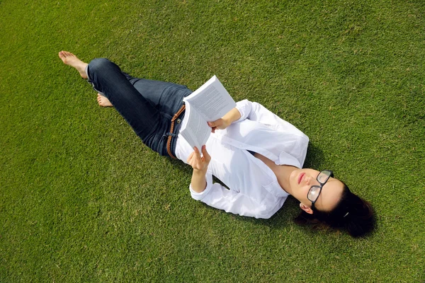 Genç bir kadın parkta kitap okuyor. — Stok fotoğraf