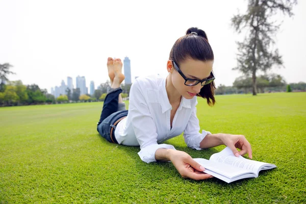 公園で本を読んでいる若い女性が — ストック写真