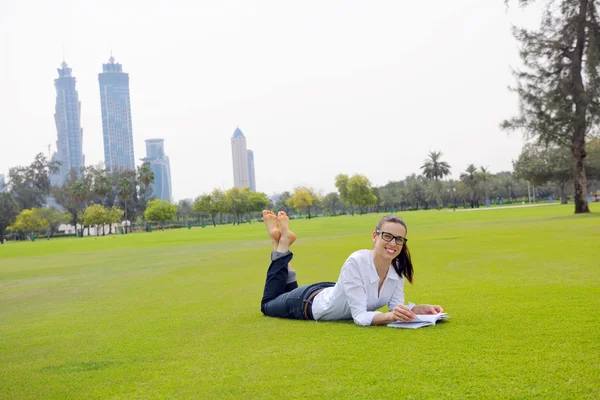 Jonge vrouw leest een boek in het park — Stockfoto