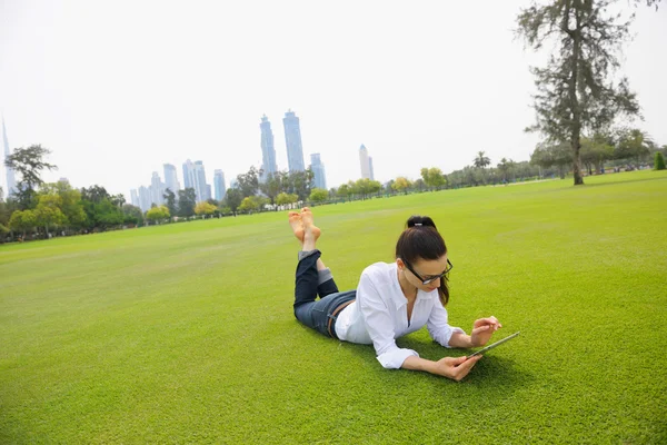 Mooie jonge vrouw met tablet in park — Stockfoto