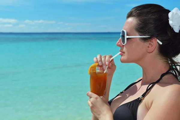 Mooie jonge vrouw met een drankje bij de zee — Stockfoto