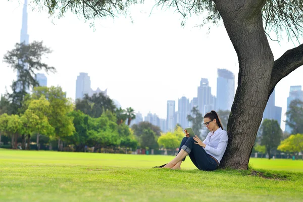 Mooie jonge vrouw met tablet in park — Stockfoto