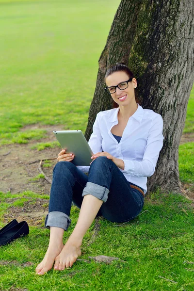 Bella giovane donna con tablet nel parco — Foto Stock