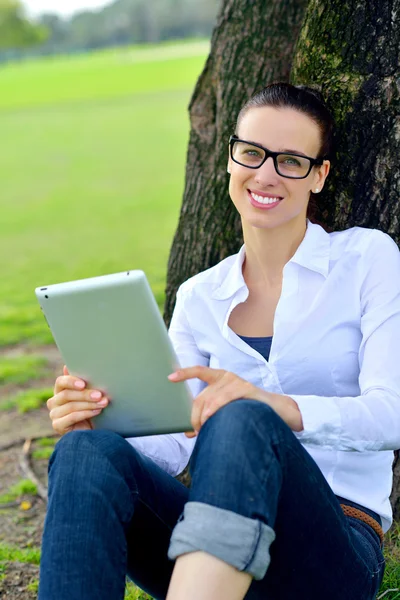 Bella giovane donna con tablet nel parco — Foto Stock