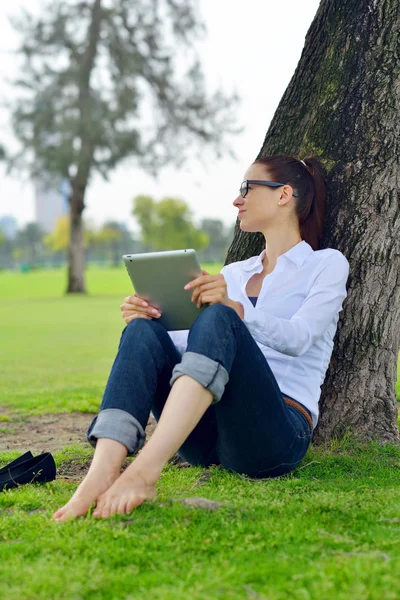 Beautiful young woman with tablet in park — Stock Photo, Image