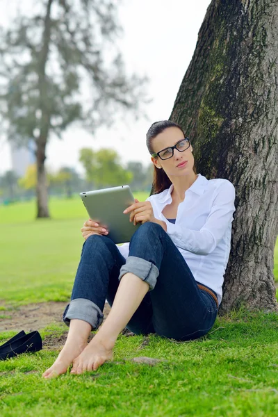 Beautiful young woman with tablet in park — Stock Photo, Image