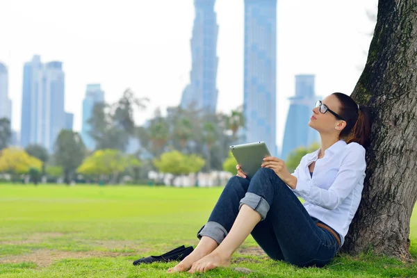 Beautiful young woman with tablet in park — Stock Photo, Image