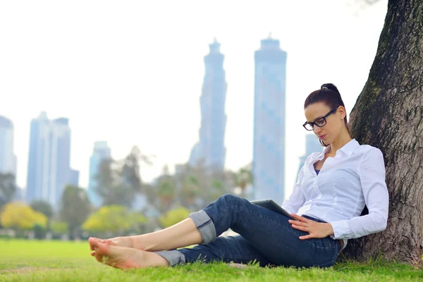 Bella giovane donna con tablet nel parco — Foto Stock