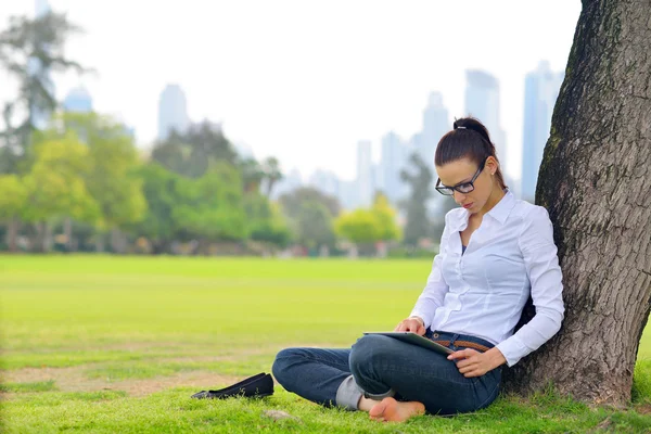 Beautiful young woman with tablet in park — Stock Photo, Image