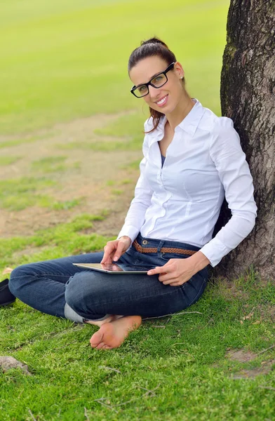 Bella giovane donna con tablet nel parco — Foto Stock