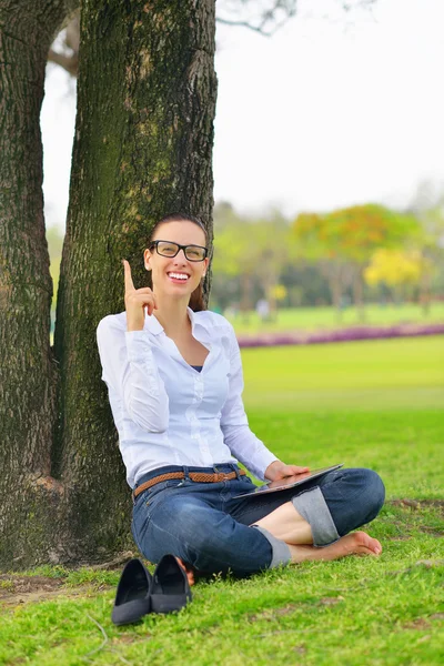 Vacker ung kvinna med tablett i park — Stockfoto