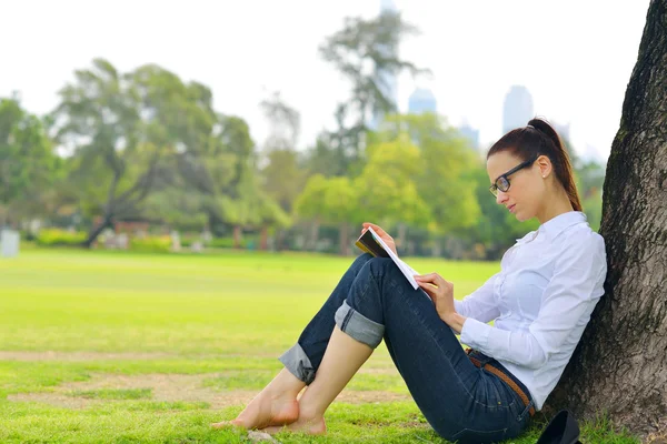 公園で本を読んでいる若い女性が — ストック写真