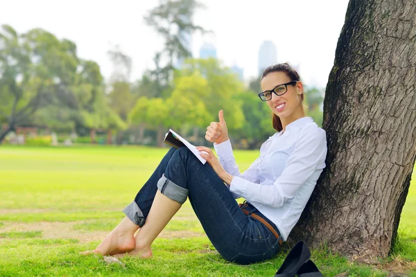 Genç bir kadın parkta kitap okuyor. — Stok fotoğraf