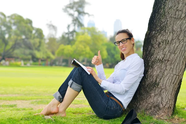 Ung kvinna läser en bok i parken — Stockfoto