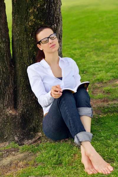 Jeune femme lisant un livre dans le parc — Photo