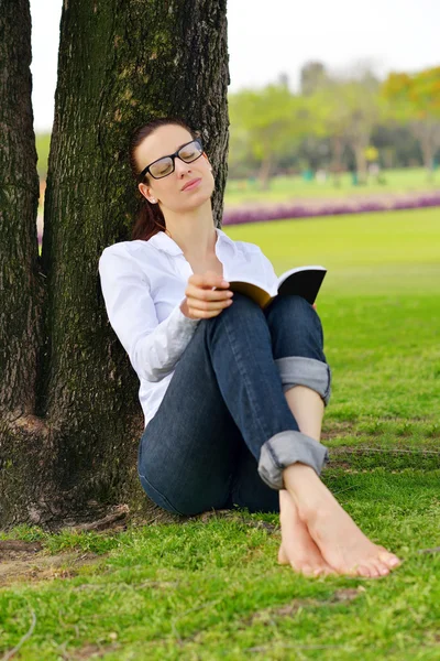 Genç bir kadın parkta kitap okuyor. — Stok fotoğraf