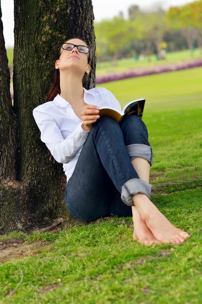 Jeune femme lisant un livre dans le parc — Photo