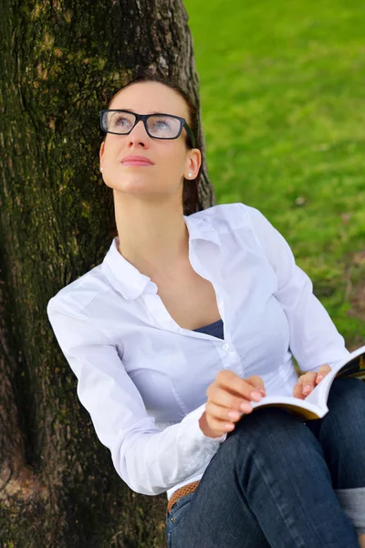 Genç bir kadın parkta kitap okuyor. — Stok fotoğraf