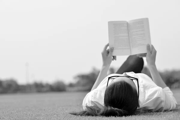 Genç bir kadın parkta kitap okuyor. — Stok fotoğraf
