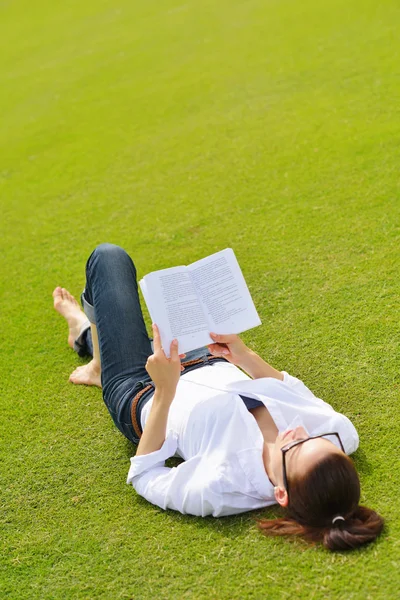 Jonge vrouw leest een boek in het park — Stockfoto