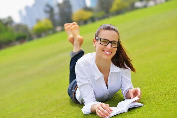 Jonge vrouw leest een boek in het park — Stockfoto