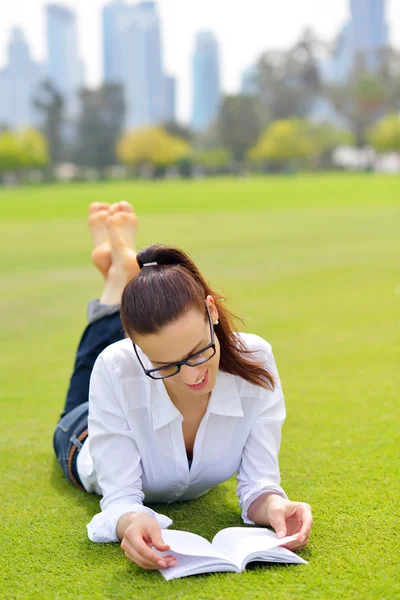 公園で本を読んでいる若い女性が — ストック写真