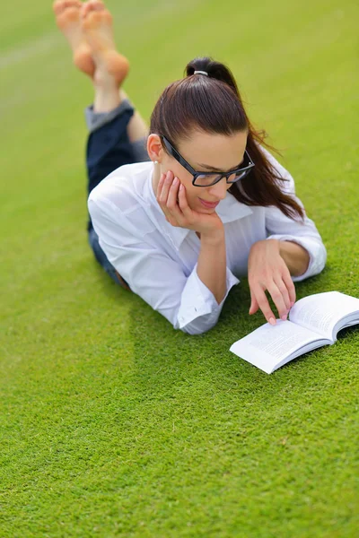 公園で本を読んでいる若い女性が — ストック写真