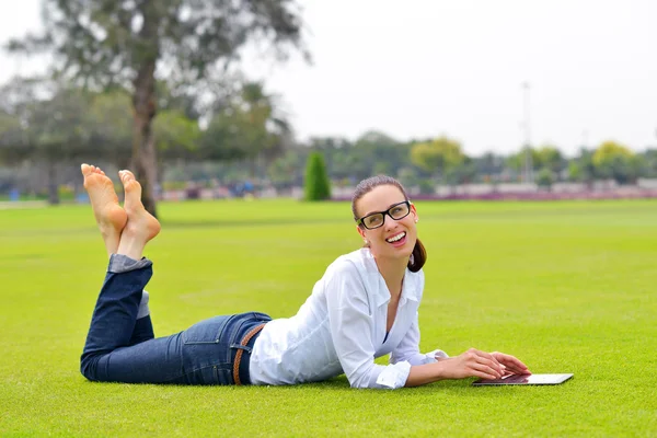 Beautiful young woman with tablet in park — Stock Photo, Image