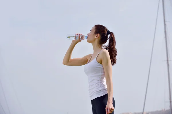 Молода красива жінка п'є воду після фізичних вправ — стокове фото