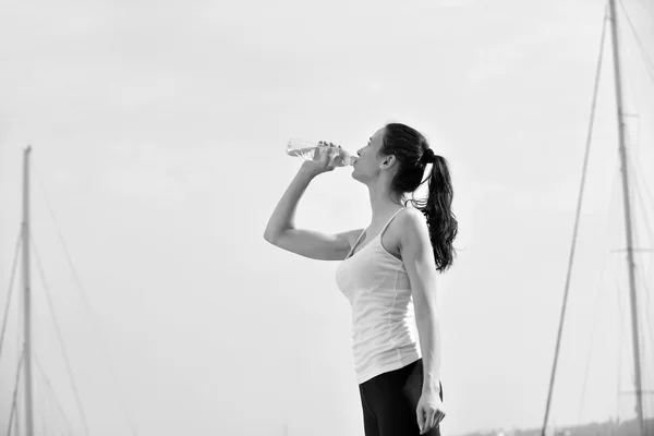 Young beautiful woman drinking water after fitness exercise — Stock Photo, Image