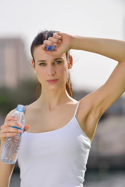 Молода красива жінка п'є воду після фізичних вправ — стокове фото