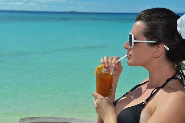 Hermosa joven con una bebida junto al mar — Foto de Stock