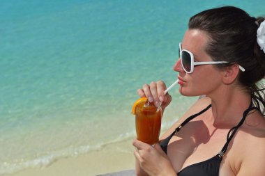 Deniz kenarında bir içkiyle güzel genç kadın